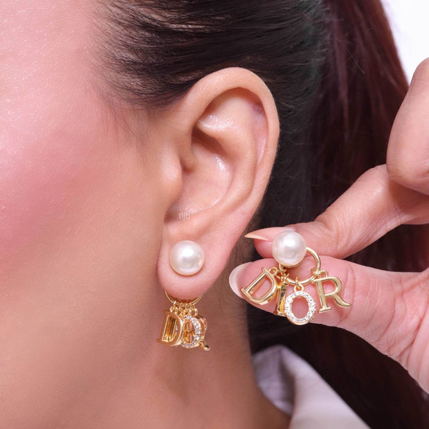 Alphabet CD dangling pearl studs in gold finish with CZ