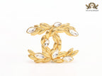 Twin C brooch in matte gold and fancy cz