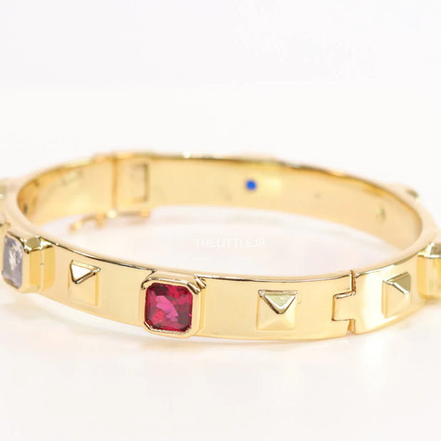 Band style bracelet in gold plating with gold plated details and ruby red colour stones