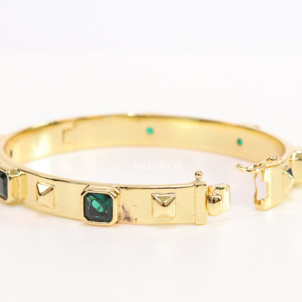 Band style bracelet in gold plating with gold plated details and emerald green colour stones