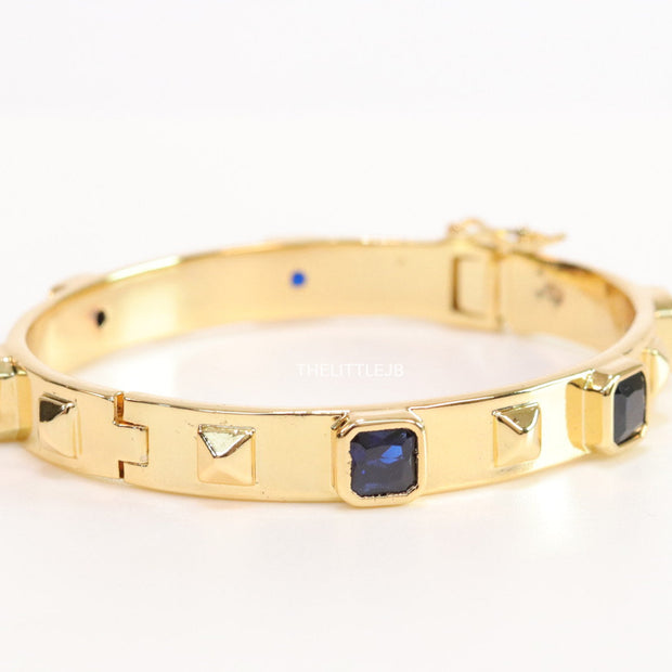 Band style bracelet in gold plating with gold plated details and sapphire blue colour stones
