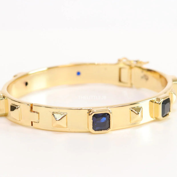 Band style bracelet in gold plating with gold plated details and sapphire blue colour stones