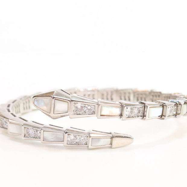 Open top platinum plated minimal serpentine bracelet with cubic zirconia stones and pearl white stones.