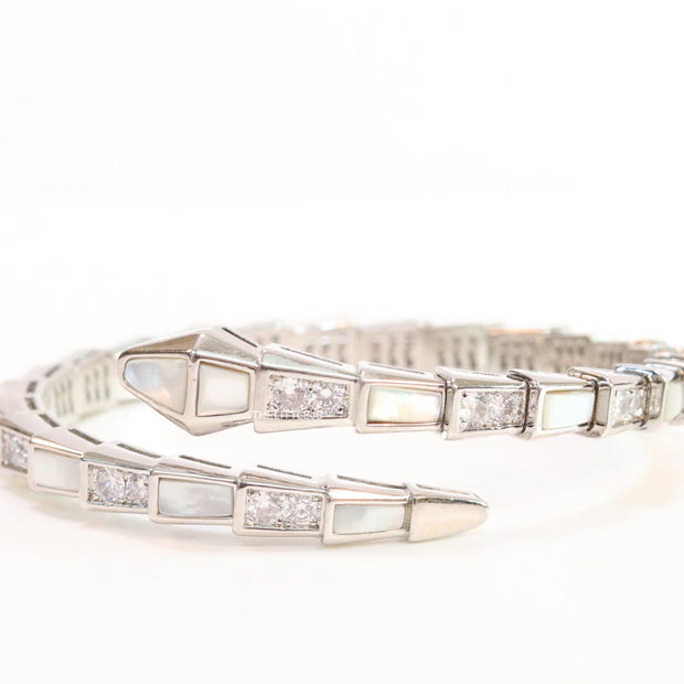 Open top platinum plated minimal serpentine bracelet with cubic zirconia stones and pearl white stones.