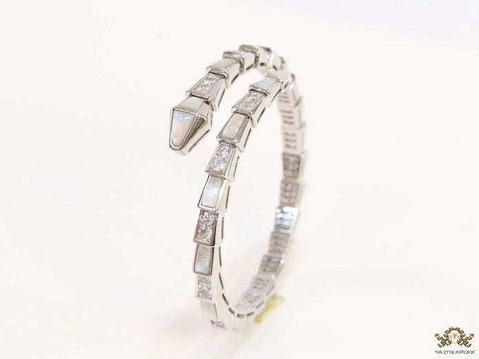 Open top platinum plated minimal serpentine bracelet with cubic zirconia stones and pearl white stones.