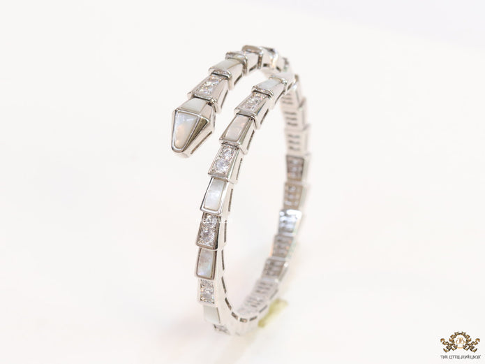 Open top platinum plated minimal serpentine bracelet with cubic zirconia stones and pearl white stones.