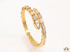 Open top gold plated minimal serpentine bracelet with cubic zirconia stones and pearl white stones.