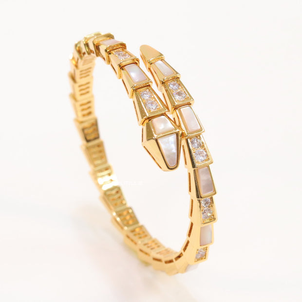 Open top gold plated minimal serpentine bracelet with cubic zirconia stones and pearl white stones.