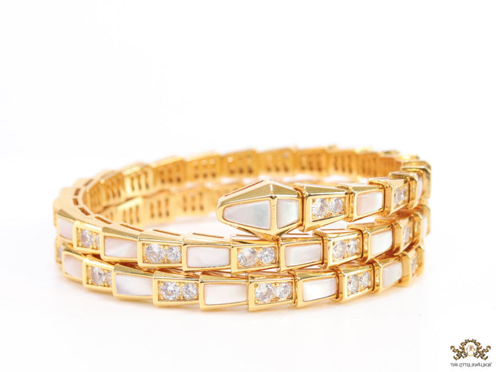 Triple line gold plated minimal serpentine bracelet with cubic zirconia stones and pearl white stones.