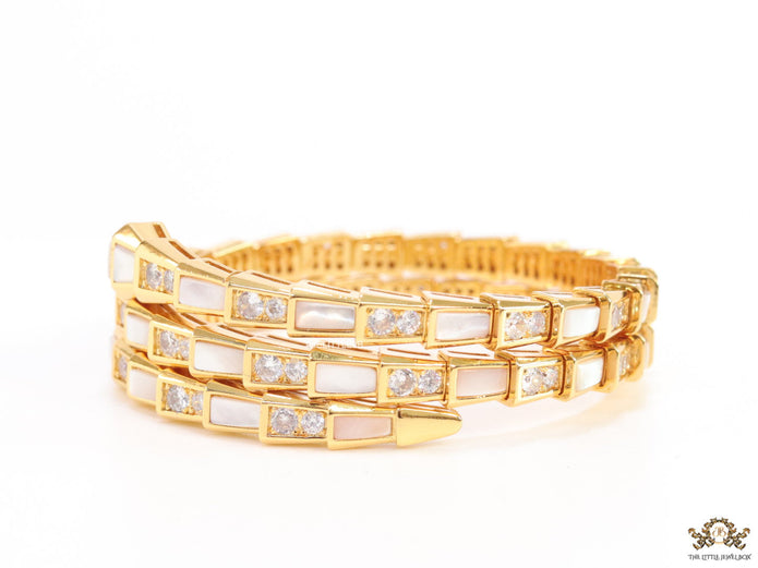 Triple line gold plated minimal serpentine bracelet with cubic zirconia stones and pearl white stones.
