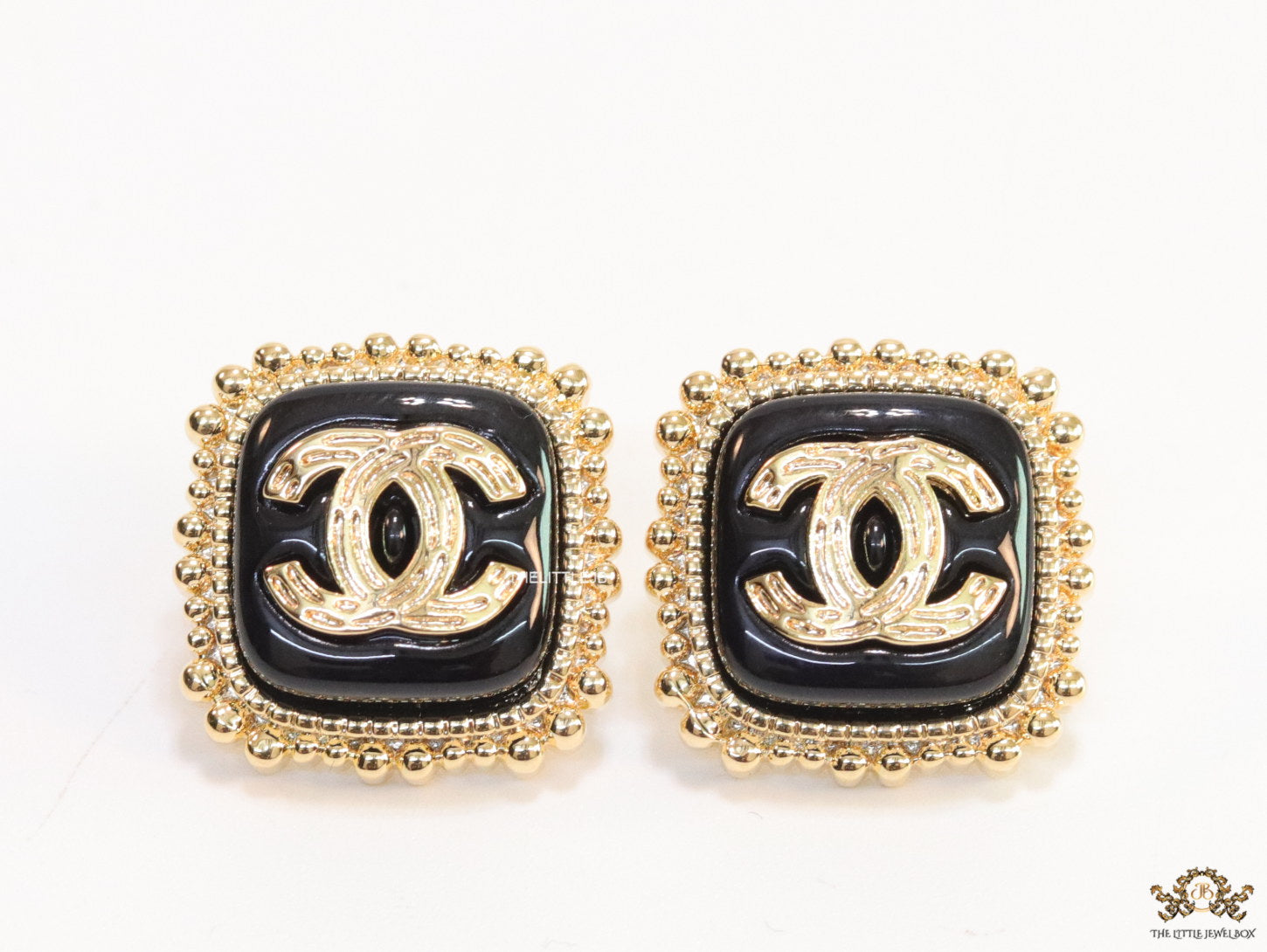 Square black and golden stud earrings with golden twin C motifs