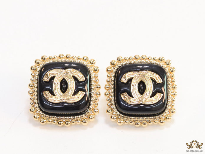 Square black and golden stud earrings with golden twin C motifs