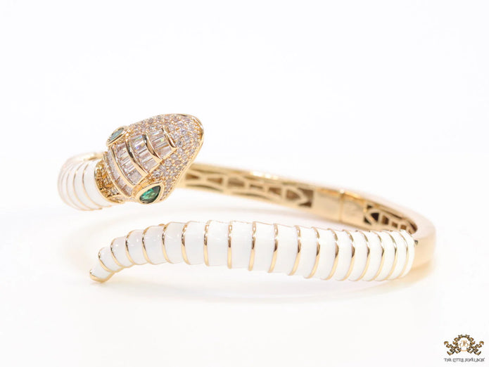 Top open serpentine bracelet in white enamel with  gold plated details and cubic zirconia stones head
