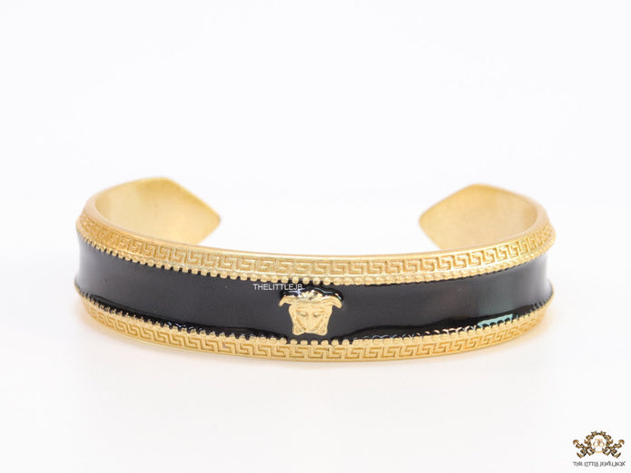 Band style black enamel bracelet with gold plated details and gold plated Medusa face motif