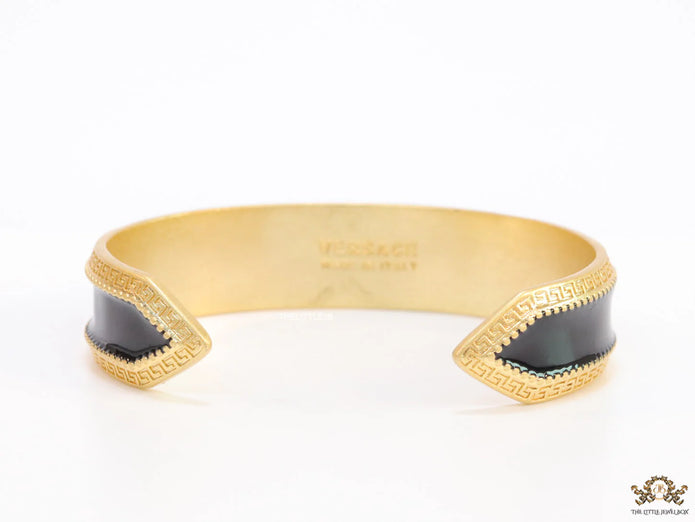 Band style black enamel bracelet with gold plated details and gold plated Medusa face motif