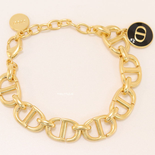 Gold plated link chain bracelet with charms, trinkets and black enamel charm with alphabets