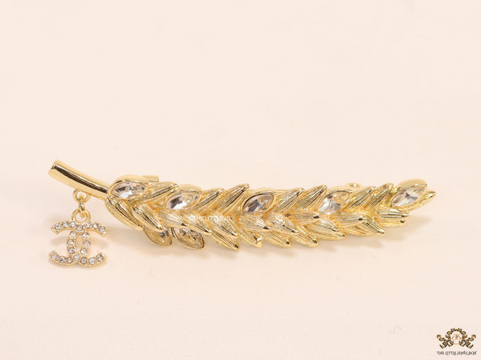 Golden feather brooch with fancy cz and twin C charm