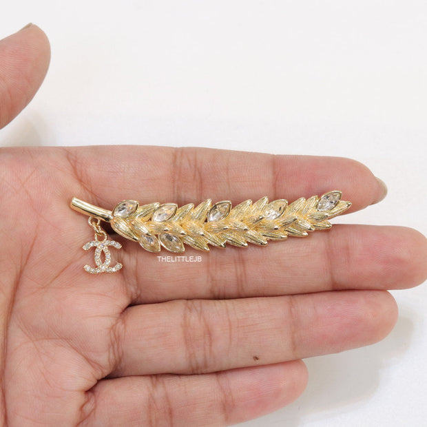 Golden feather brooch with fancy cz and twin C charm