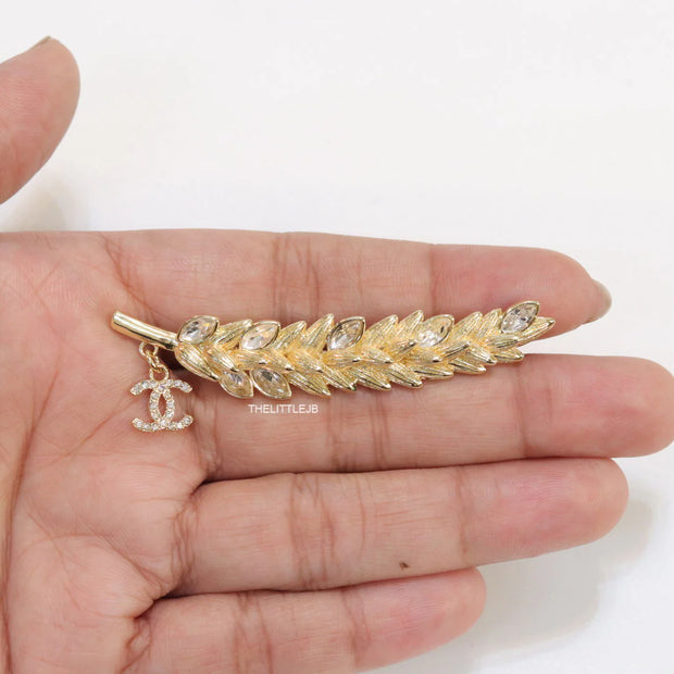Golden feather brooch with fancy cz and twin C charm