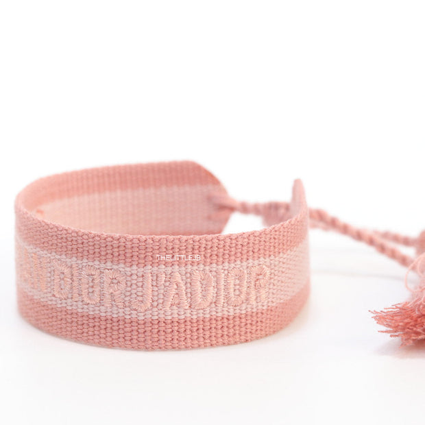 Adjustable pastel pink woven bracelet with knitted alphabets and tassels