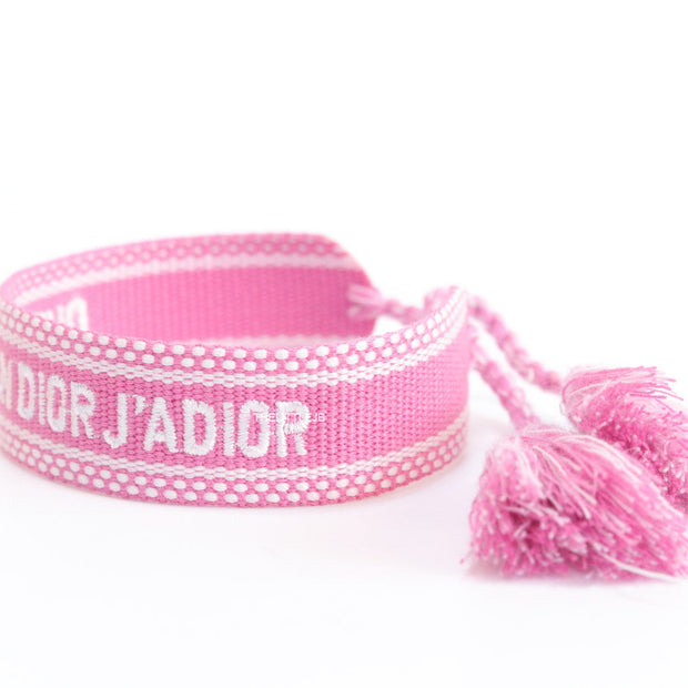 Adjustable pink woven bracelet with white knitted alphabets and tassels