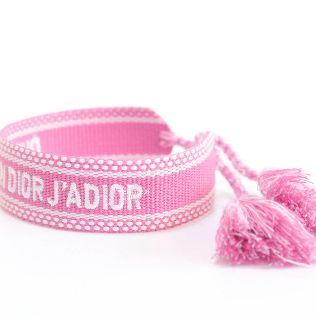Adjustable pink woven bracelet with white knitted alphabets and tassels