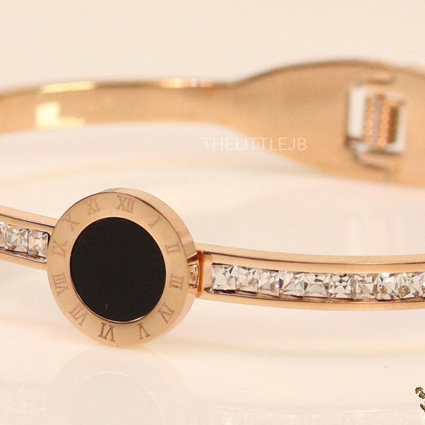 Rose gold plated cz bracelet with roman numerals inscribed on black centre motif