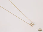 Gold chain necklace with white enamel H motif