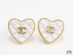 White textured heart shaped studs with twin C motif in golden finish