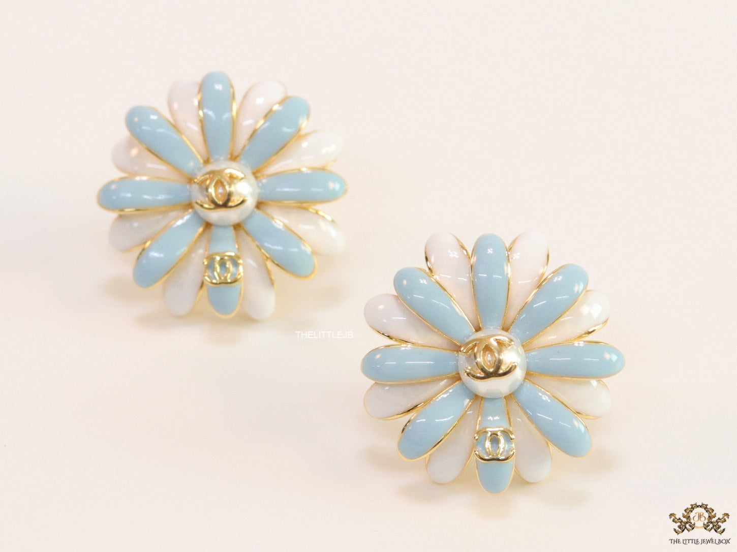 Off-white and soft blue daisy studs with golden details twin alphabet double C motif.