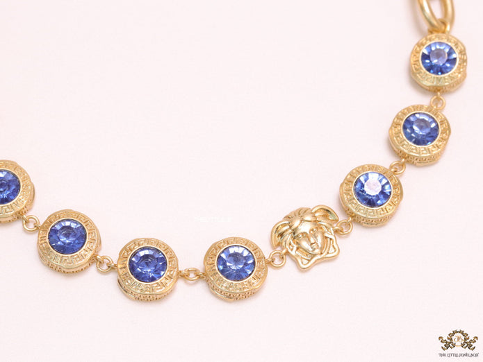 Gold plated link chain with blue cubic zirconia stones and gold plated Medusa motif charm.