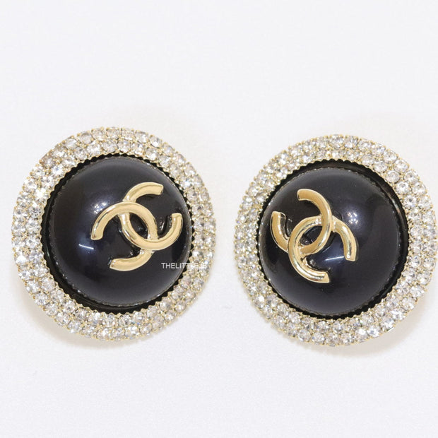 Round black stud earrings with golden twin C motifs lined with cz