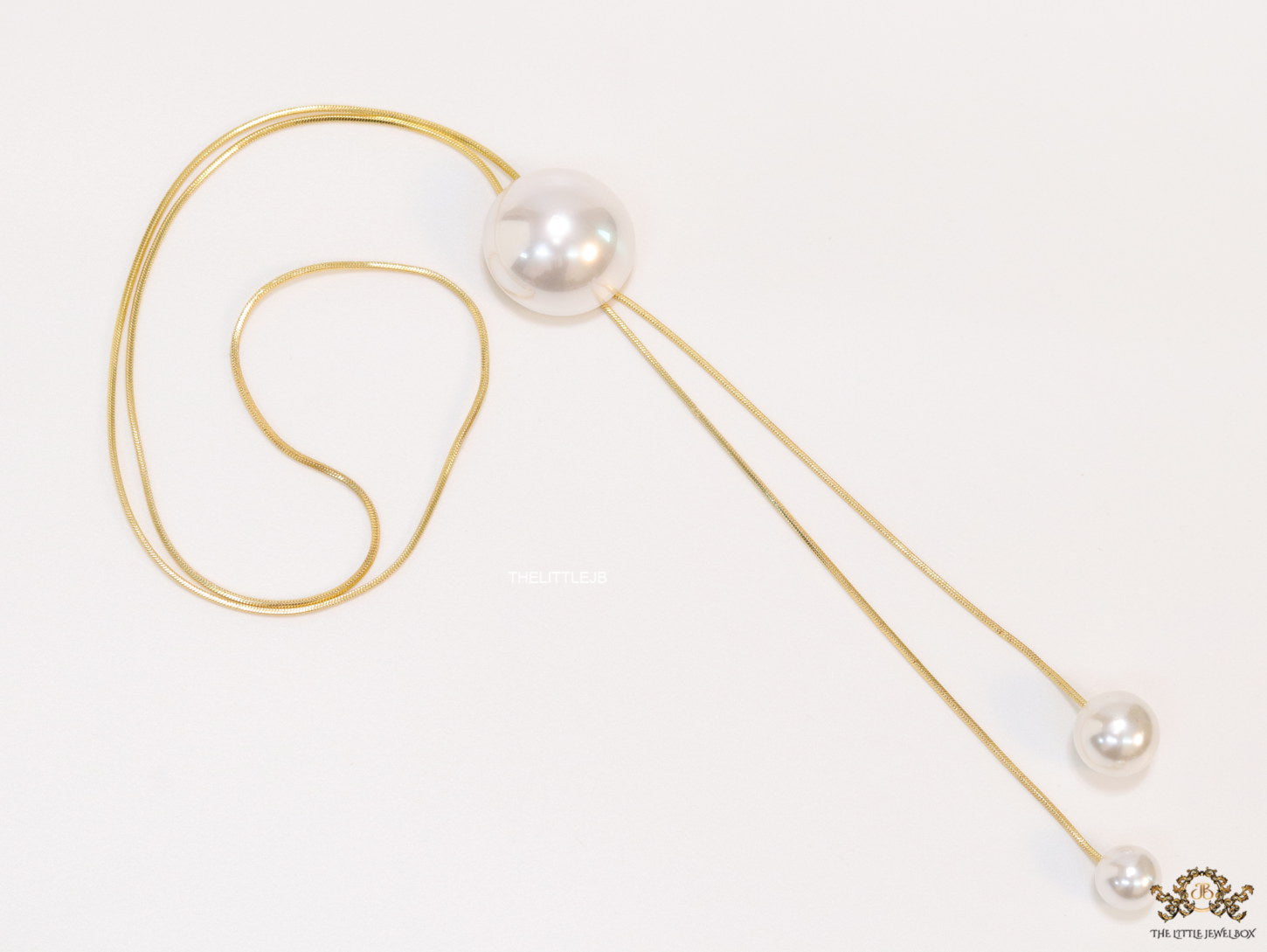Sleek gold plated chain with different sized shell pearls.