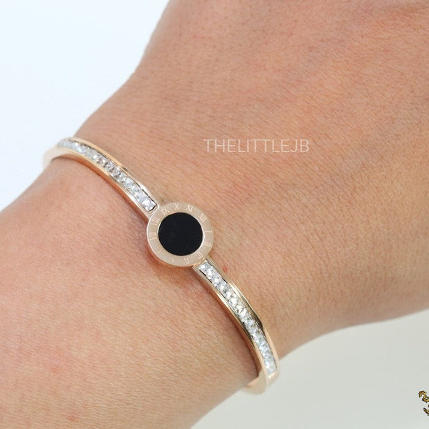 Rose gold plated cz bracelet with roman numerals inscribed on black centre motif