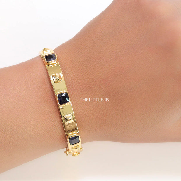 Band style bracelet in gold plating with gold plated details and sapphire blue colour stones