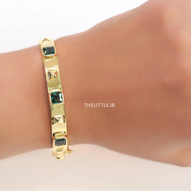 Band style bracelet in gold plating with gold plated details and emerald green colour stones