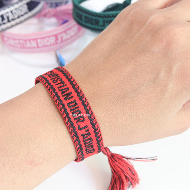 Adjustable red woven bracelet with black knitted alphabets and tassels