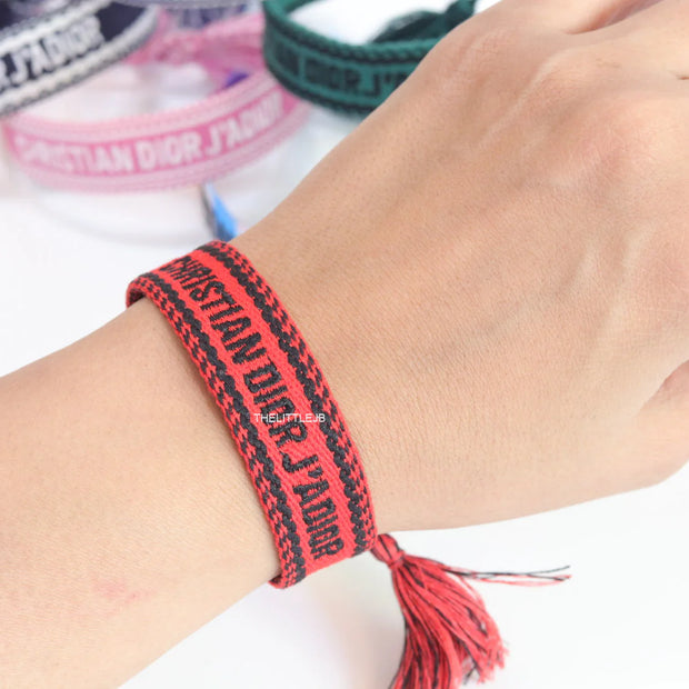 Adjustable red woven bracelet with black knitted alphabets and tassels