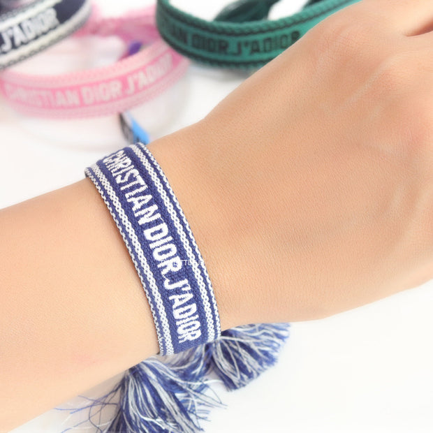 Adjustable blue woven bracelet with white knitted alphabets and tassels