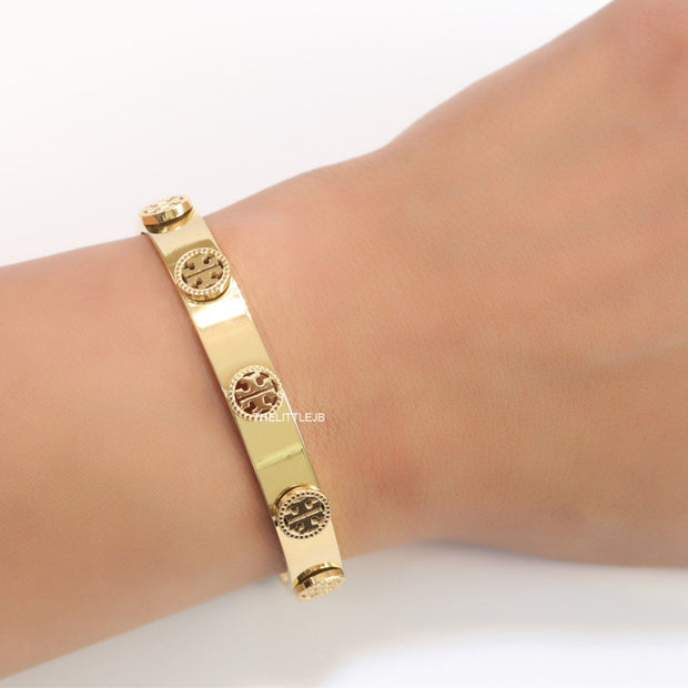 Gold plated open band bracelet with twin T motifs