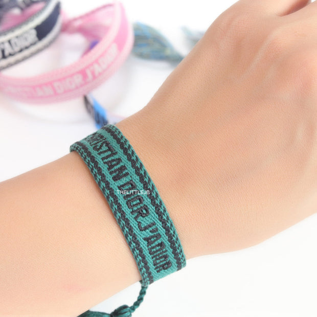 Adjustable green woven bracelet with black knitted alphabets and tassels