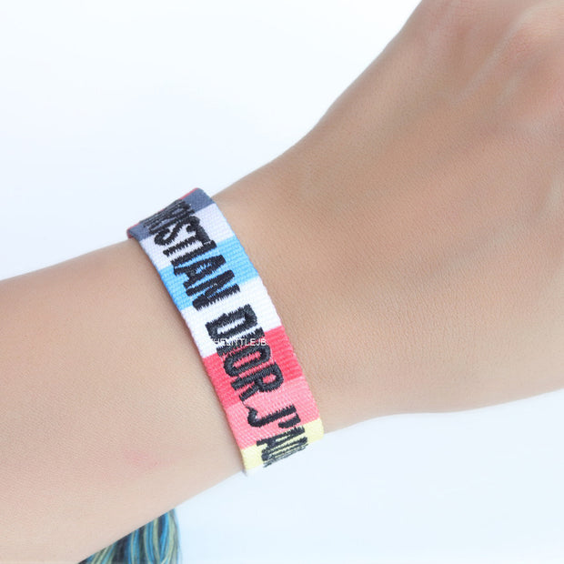 Adjustable multi color woven bracelet with black knitted alphabets and tassels