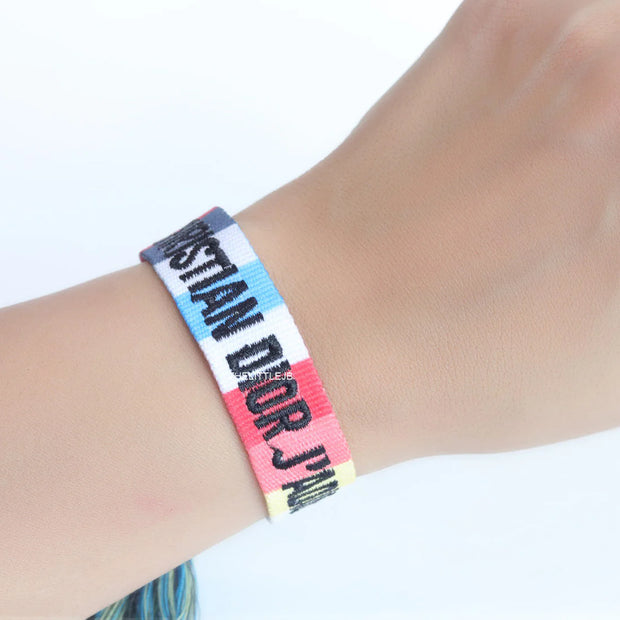 Adjustable multi color woven bracelet with black knitted alphabets and tassels