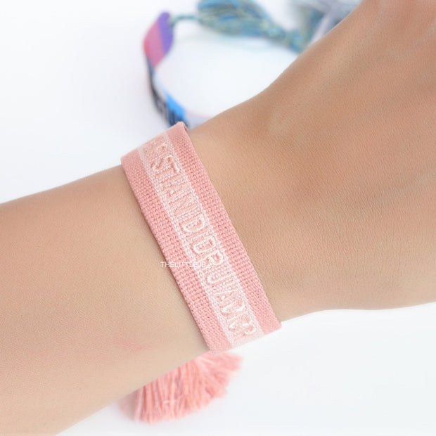 Adjustable pastel pink woven bracelet with knitted alphabets and tassels