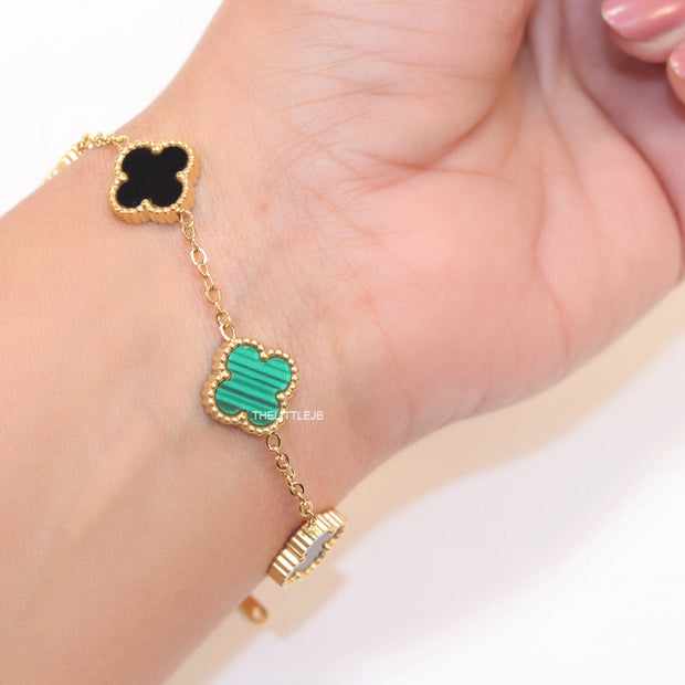 Golden chain bracelet with black and green clovers