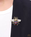 Antique gold finish double G bee brooch with blue details and white and red stones
