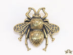 Antique gold finish bee brooch with white and red stones and blue details