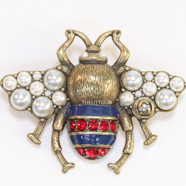 Antique gold finish double G bee brooch with blue details and white and red stones
