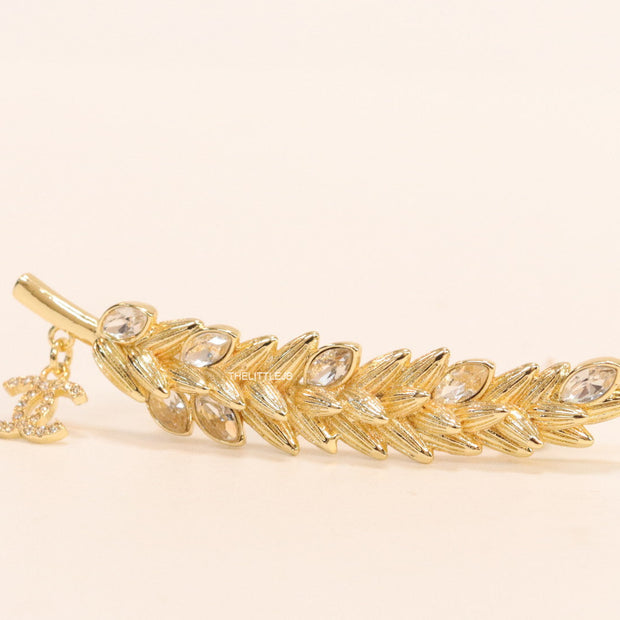 Golden feather brooch with fancy cz and twin C charm