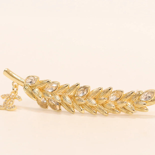 Golden feather brooch with fancy cz and twin C charm